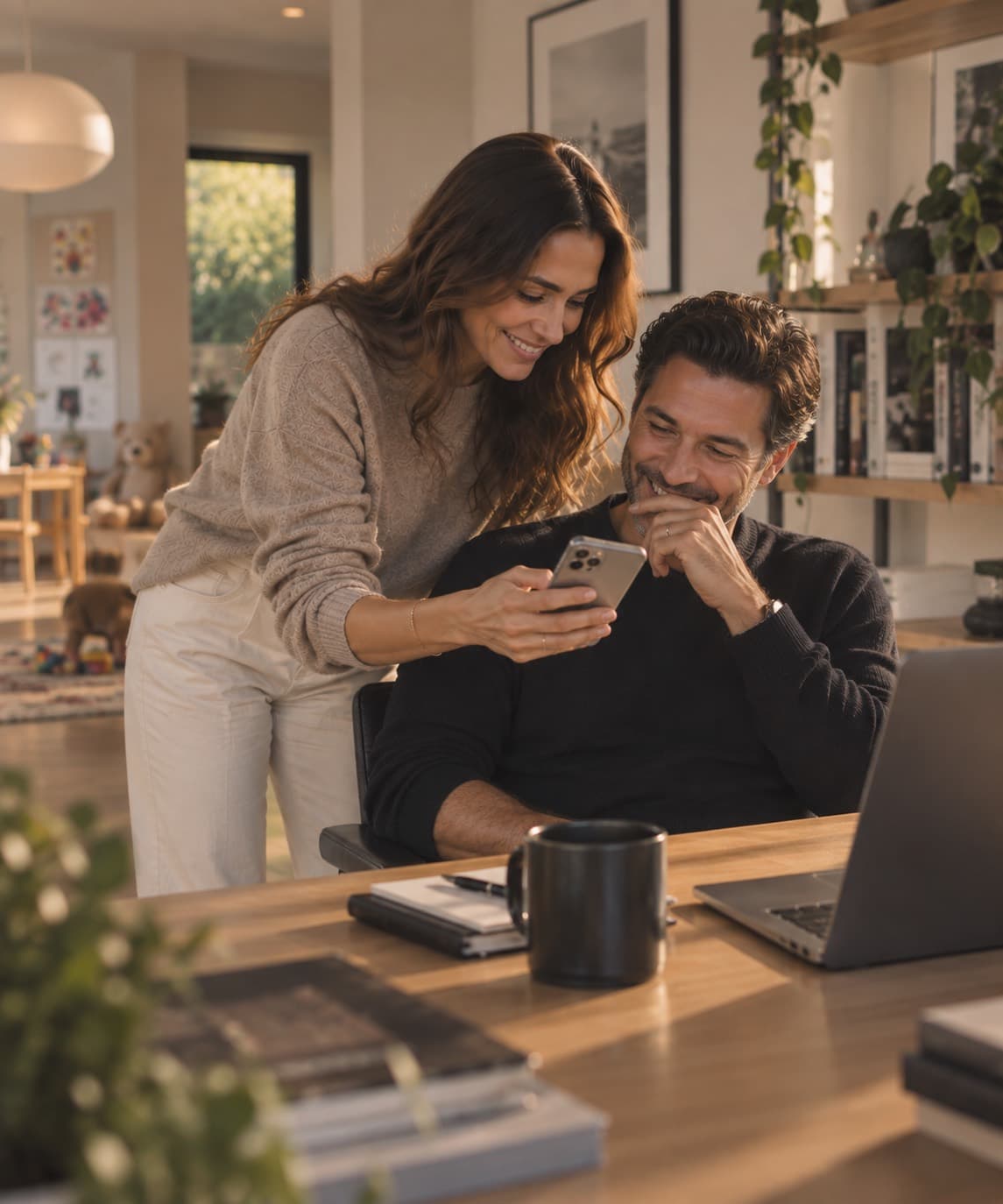 Two parents at home smiling at an update on a phone